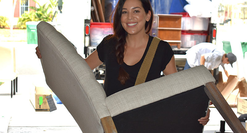 Designer Carolina Chavez carrying a chair for Sergeant Perez's home furnishing project