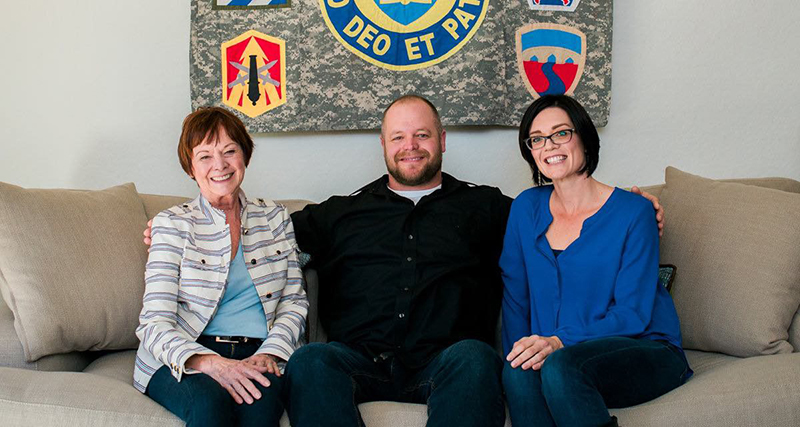 Beth Phillips with a wounded veteran and his wife seated on a sofa in their furnished home